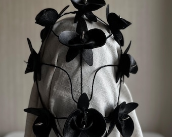 Die zarte Form einer Orchidee in schwarzem Leder, ein Dorn zwischen den Blütenblättern verborgen. 30 Stunden Handarbeit.