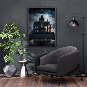 May include: A framed wall art print depicting a dark, multi-story mansion at night under a full moon, with illuminated windows and a reflection in the foreground water. The artwork is displayed on a dark wall above a gray upholstered armchair.