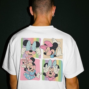 May include: White t-shirt featuring a colorful graphic of Minnie Mouse in four different poses. Each pose is set against a pastel background. The design includes Minnie's signature bow and polka dots.