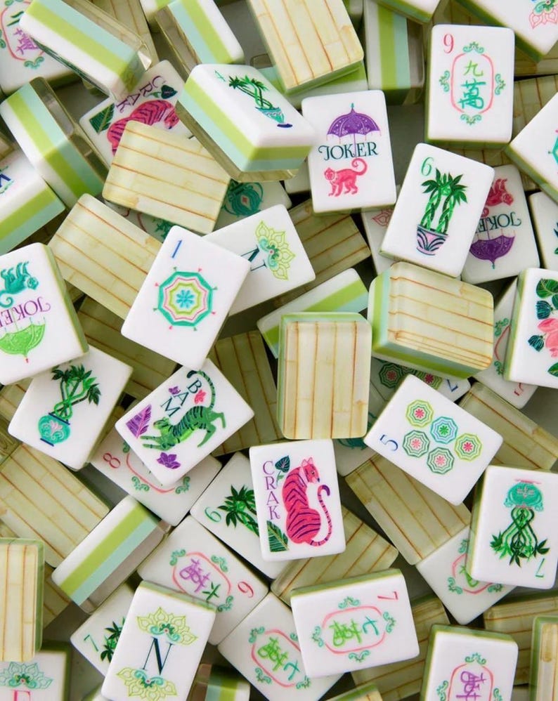 May include: A collection of white and green Mahjong tiles with various symbols and characters. Some tiles feature illustrations of a tiger, monkey, and palm trees. The tiles are arranged in a random pattern.