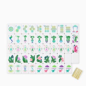May include: A complete Mahjong set with white tiles featuring colorful illustrations of flowers, plants, and geometric designs. The set includes tiles with numbers, suits, and Jokers, along with a wooden tile holder.