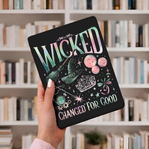 Może przedstawiać: Czarne etui na tablet z napisem "WICKED" dużymi, kolorowymi literami. Etui zawiera ilustracje kapelusza czarownicy, miotły, korony oraz napis "CHANGED FOR GOOD".