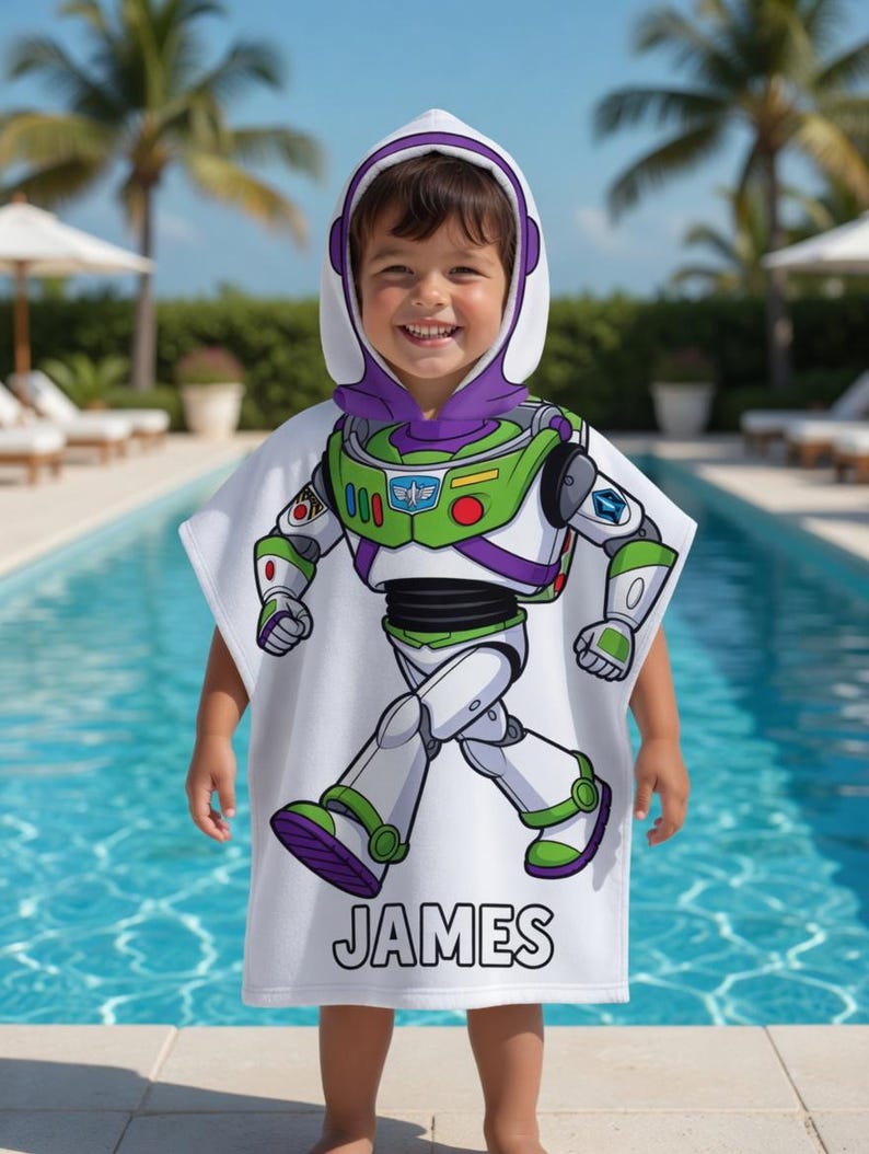 Puede incluir: Una toalla con capucha blanca con un dise&ntilde;o de Buzz Lightyear. La toalla presenta un gr&aacute;fico de cuerpo completo del personaje, con detalles verdes, morados y blancos. El nombre "JAMES" est&aacute; impreso en negro. El ni&ntilde;o est&aacute; junto a una piscina.