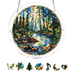 May include: A round stained glass window depicting a forest scene with a river, trees, and sunlight. The window is framed in clear plastic and has a chain for hanging. Includes decorative stained glass shapes of a butterfly, leaf, tree, flower, musical note, moon, and heart.
