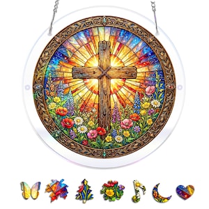May include: A circular stained glass suncatcher featuring a wooden cross centred against a radiant sunburst background, surrounded by colourful wildflowers including poppies and daisies, framed in an ornate bronze border with a hanging chain.