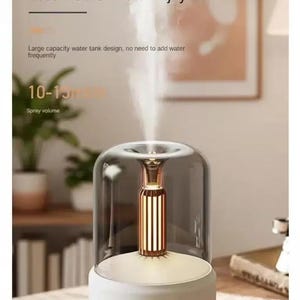 Pu&ograve; includere: Un umidificatore d'aria bianco e trasparente con dettagli dorati. Il dispositivo ha un design del serbatoio dell'acqua di grande capacit&agrave;, come indicato nel testo. Il testo sul dispositivo recita "SUSTAIN ALL DAY" e "Less Refills. More Enjoyment."