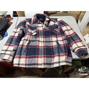 May include: A checked jacket in red, navy blue, and cream. The jacket features a button-up front, two chest pockets, and two side pockets. The collar and pocket trim are navy blue.