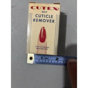 May include: A vintage Cutex Oily Cuticle Remover box, approximately 5 cm long, with a red nail polish design. The box is cream-coloured with red and blue text. Includes a cotton and manicure stick.