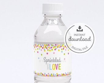 Könnte beinhalten: Eine durchsichtige Plastikwasserflasche mit einem weißen Etikett, auf dem "Sprinkled with LOVE" steht. Das Etikett ist mit bunten Konfetti verziert. Die Flasche steht auf einem weißen Hintergrund.