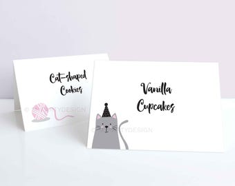 Könnte beinhalten: Zwei bedruckbare Lebensmitteletiketten mit einer niedlichen Comic-Katze, die einen Partyhut trägt. Das erste Etikett lautet "Cat-shaped Cookies" und das zweite Etikett lautet "Vanilla Cupcakes".