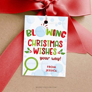 May include: A white gift tag with the text "Blowing Christmas Wishes your way!" in green and red. The tag includes a green magnifying glass graphic and is tied with a red ribbon.