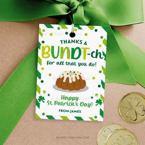 May include: A St. Patrick's Day gift tag with a green ribbon. The tag reads "Thanks a Bundt-ch for all that you do!" and features a cartoon bundt cake and shamrocks. Gold coins are in the background.