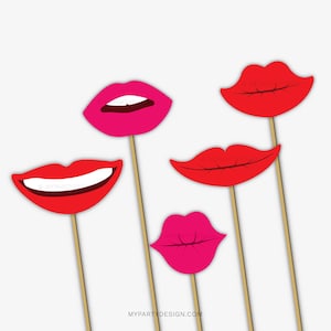 May include: Five lip-shaped photo booth props in shades of red and pink, each attached to a wooden stick. The lips are in various styles, some smiling, others closed. The background is a plain white.