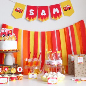 Puede incluir: Decoraciones de fiesta de cumplea&ntilde;os con tem&aacute;tica de cami&oacute;n de bomberos con serpentinas de papel rojo, amarillo y naranja, un pastel con un adorno de cami&oacute;n de bomberos, cupcakes con adornos de cami&oacute;n de bomberos y bolsas de regalo con dise&ntilde;os de camiones de bomberos. La pancarta dice "SAM".