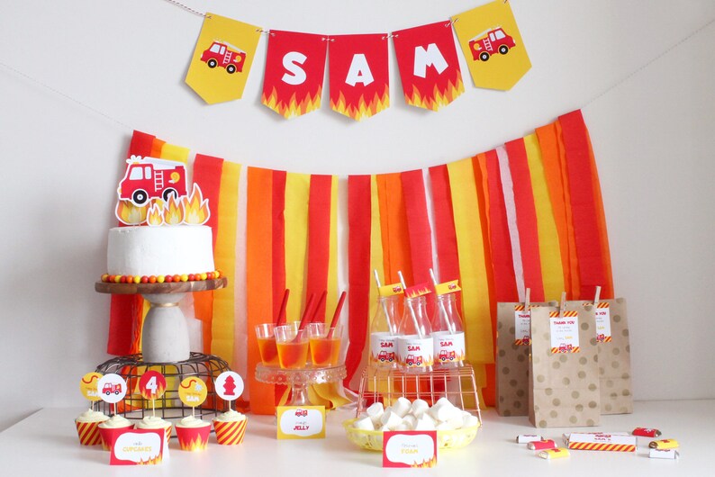 Puede incluir: Decoraciones de fiesta de cumplea&ntilde;os con tem&aacute;tica de cami&oacute;n de bomberos con serpentinas de papel rojo, amarillo y naranja, un pastel con un adorno de cami&oacute;n de bomberos, cupcakes con adornos de cami&oacute;n de bomberos y bolsas de regalo con dise&ntilde;os de camiones de bomberos. La pancarta dice "SAM".