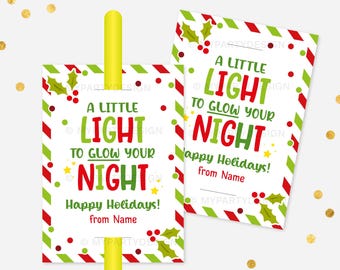 May include: Two holiday gift tags with a festive design. The tags feature the text "A Little Light to Glow Your Night" in red and green, with holly and star accents. The tags are bordered with red and green stripes and include space to write a name.