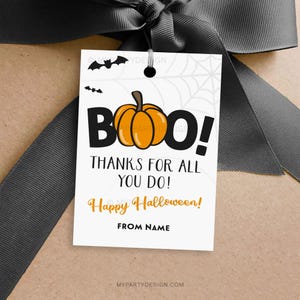 Könnte beinhalten: Ein weißes Halloween-Geschenkanhänger mit einem grauen Band. Der Anhänger zeigt eine Kürbisgrafik mit dem Wort "BOO!" und dem Text "THANKS FOR ALL YOU DO!" und "Happy Halloween!". Der Anhänger ist an einem braunen Paket befestigt.