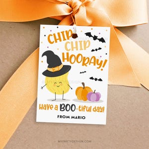 May include: A Halloween-themed gift tag with an orange bow. The tag features a cartoon chip character wearing a witch hat, pumpkins, and bats. Text includes "Chip Chip Hooray!" and "Have a BOO-tiful day!"