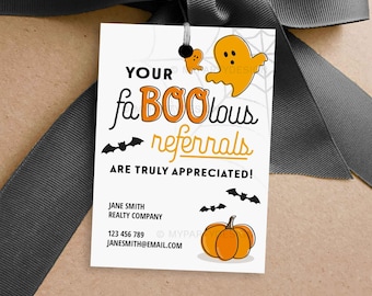 May include: A Halloween-themed gift tag with a gray ribbon. The tag features orange and black graphics of ghosts, bats, and a pumpkin. Text on the tag reads "YOUR faBOOlous referrals ARE TRULY APPRECIATED!" and includes contact information.