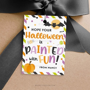 以下が含まれることがあります： 「HOPE YOUR Halloween is PAINTED with FUN!」と書かれた、ハロウィーンをテーマにしたギフトタグ。カボチャ、コウモリ、月のグラフィックが特徴で、濃い灰色のリボンで結ばれています。