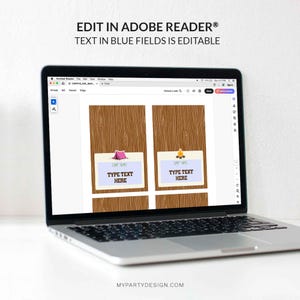 May include: A laptop displays a digital invitation template with a camping theme. The design features a wooden background with illustrations of a tent and campfire. The text "EDIT IN ADOBE READER&reg; TEXT IN BLUE FIELDS IS EDITABLE" is visible.