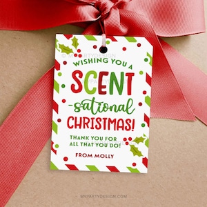 Könnte beinhalten: Ein weißes Geschenk-Etikett mit roten und grünen Akzenten, mit dem Text "Wishing You a Scent-sational Christmas!" und "Thank You for All That You Do!" mit einem roten Band gebunden. Das Etikett enthält Stechpalmen-Illustrationen und ist mit "From Molly" signiert.