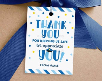 Puede incluir: Etiqueta de agradecimiento azul y blanca con un gráfico de sombrero de policía. La etiqueta dice "Gracias por mantenernos seguros. ¡Te apreciamos!" y "De [Nombre]".
