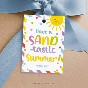 May include: A white gift tag with the text "Have a SAND-tastic Summer!" in colorful letters, a smiling sun graphic, and the name "LILY". The tag is tied with a light blue ribbon.
