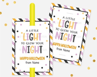 May include: Two Halloween-themed gift tags with the text "A Little Light to Glow Your Night" in orange, purple, and black. The tags have a white background with black, orange, and purple accents. A yellow straw is inserted through one tag.