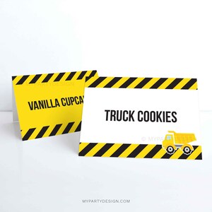 May include: Two yellow and black construction themed food labels. The first label says "Vanilla Cupcakes". The second label says "Truck Cookies" and has a small yellow dump truck graphic.