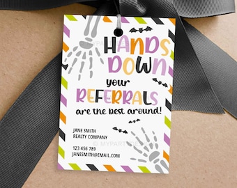 May include: A white gift tag with the text "HANDS DOWN your REFERRALS are the best around!" in purple, orange, and black. The tag has a black border with skeleton hands and bats. The tag is tied with a gray ribbon.