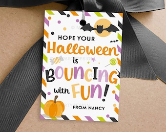May include: A Halloween-themed gift tag with a black bat silhouette, a full moon, and the words "HOPE YOUR Halloween is BOUNCING with FUN!" in colorful text. An orange pumpkin and a swirl lollipop are also featured.