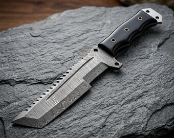 May include: A fixed-blade knife featuring a Damascus steel blade with a serrated spine and a distinct wavy pattern. The handle is made of smooth black material, secured with three metallic rivets, and includes a metallic pommel with a lanyard hole.