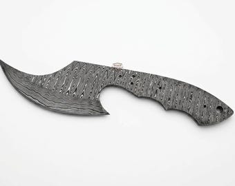 May include: A Damascus steel knife blade with a curved, pointed tip and a handle-shaped tang. The blade has a distinctive pattern of swirling lines, and the tang features several holes for attachment.