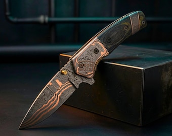 May include: A handcrafted folding knife with a patterned blade and copper accents. The handle is dark wood with copper and black hardware. The blade has a unique pattern with copper-colored accents. The knife is displayed on a dark surface.