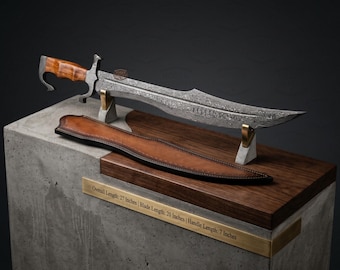 May include: A Damascus steel sword with a curved blade and a wooden handle, accompanied by a brown leather sheath. A brass plaque states: Overall Length: 27 Inches | Blade Length: 20 Inches | Handle Length: 7 Inches. The sword rests on two stands.