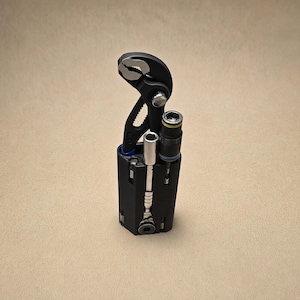 May include: A black multi-tool holder containing a set of metal tools, including a pair of black adjustable pliers with silver jaws, a silver socket wrench extension, and a black and silver socket driver with a yellow ring detail.