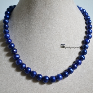 May include: A necklace made of dark blue pearls. The pearls are round and smooth, and they are strung on a thin silver chain.