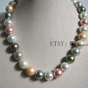 Peut inclure: Un collier de perles multicolores avec des nuances de blanc, crème, rose et vert. Le collier est composé de grosses perles rondes et est enfilé sur une chaîne argentée. Le collier est présenté sur un fond blanc. ETSY: goodgoodjewelry