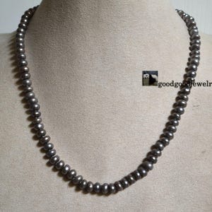 Peut inclure: Un collier de perles grises sur un mannequin. Le collier est composé de petites perles rondes.