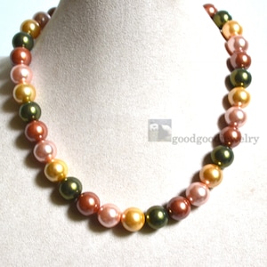 May include: A multi-colored pearl necklace with alternating shades of green, gold, and pink pearls.