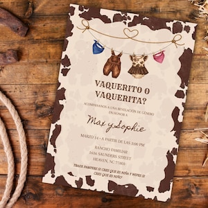 May include: A rustic invitation with a cowhide pattern border, featuring the text "VAQUERITO O VAQUERITA?" and baby clothes illustrations. The invitation is on a wooden surface with a horseshoe, rope, and hay.