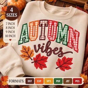 May include: A beige crewneck sweatshirt featuring the text AUTUMN in a varsity-style font with a red, green, and orange gingham pattern, followed by the word vibes in a dark brown script, and three colorful maple leaves in orange and red.