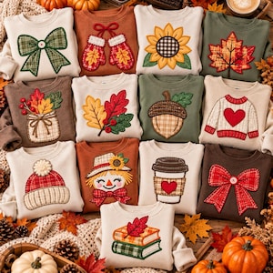 May include: A collection of twelve crewneck sweatshirts featuring various fall-themed fabric appliqués, including a green plaid bow, red mittens, a sunflower, a maple leaf, a mason jar, oak leaves, an acorn, a sweater, a beanie, a scarecrow, a coffee cup, and books.