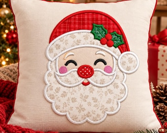 May include: A square off-white throw pillow featuring a central embroidered applique of a smiling Santa Claus face. The design includes a red plaid hat with green holly leaves and red berries, a patterned beard, and a bright red polka-dot nose.