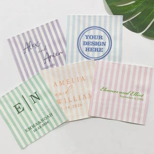 Może przedstawiać: Kolekcja spersonalizowanych serwetek w paski w pastelowych kolorach. Każda serwetka zawiera imiona i daty, a jedna z nich ma napis "YOUR DESIGN HERE". Idealne na wesela lub specjalne okazje.