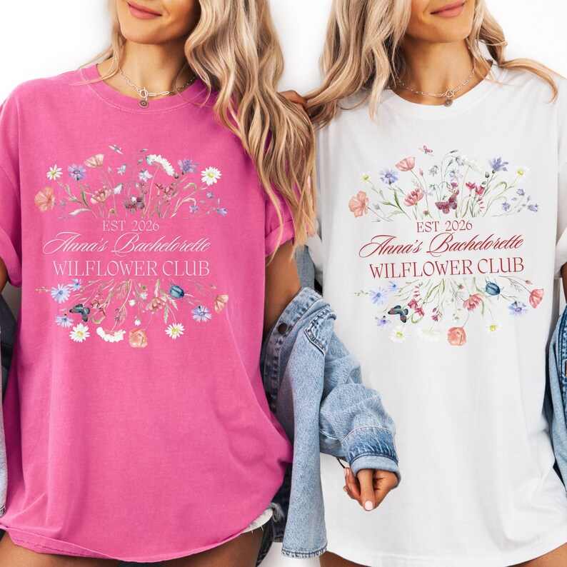 Pode incluir: Duas mulheres vestindo camisetas combinando. Uma &eacute; rosa vibrante, a outra branca. Ambas apresentam um design floral e o texto "Anna's Bachelorette WILFLOWER CLUB EST 2026". As camisetas t&ecirc;m um corte folgado.