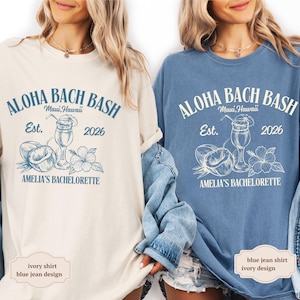 May include: Ivory and blue jean shirts with the text "ALOHA BACH BASH Maui, Hawaii Est. 2026 AMELIA'S BACHELORETTE" printed on the front. The design includes a cocktail, coconut, and hibiscus flower.