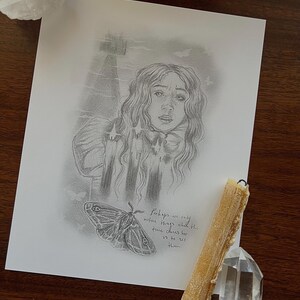 Puede incluir: Un dibujo a lápiz de una mujer con cabello largo y ondulado, una polilla y el texto "Quizás solo notemos las cosas que el tiempo elige para que las veamos". También hay una vela y cristales.