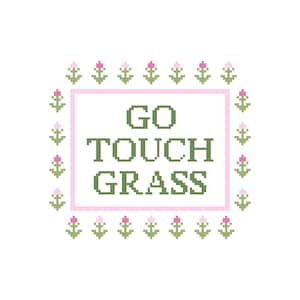 May include: A cross-stitch design with the text "GO TOUCH GRASS" in green pixelated letters, framed by a pink rectangle. The border features green and pink floral accents on a white background.